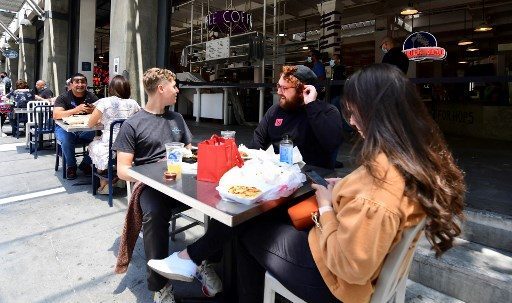  ロサンゼルス市内のレストランで食事をする人たち。再感染が広がりレストランやバーの営業が一部制限されている-ⓒAFP PHOTO /FREDERIC J. BROWN