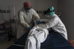 HOUSTON, TX - JUNE 30: (EDITORIAL USE ONLY) Medical staff wears full PPE as they wrap a deceased patient with bed sheets and a body bag in the Covid-19 intensive care unit at the United Memorial Medical Center on June 30, 2020 in Houston, Texas. Covid-19 cases and hospitalizations have spiked since Texas reopened, pushing intensive-care wards to full capacity and sparking concerns about a surge in fatalities as the virus spreads.   Go Nakamura/Getty Images/AFP