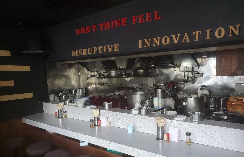 「破壊的イノベーション」の店内の様子。席を減らして営業している。「DON’T THINK FEEL」の文字には「一口食べた時に頭で考えるより全体で感じてほしい」という想いがこもる。（提供・破壊的イノベーション）