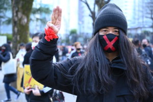 新宿で行われたデモ行進後、クーデターに抗議の意を示す「3本指」を掲げる保芦宏亮＝2021年12月26日撮影